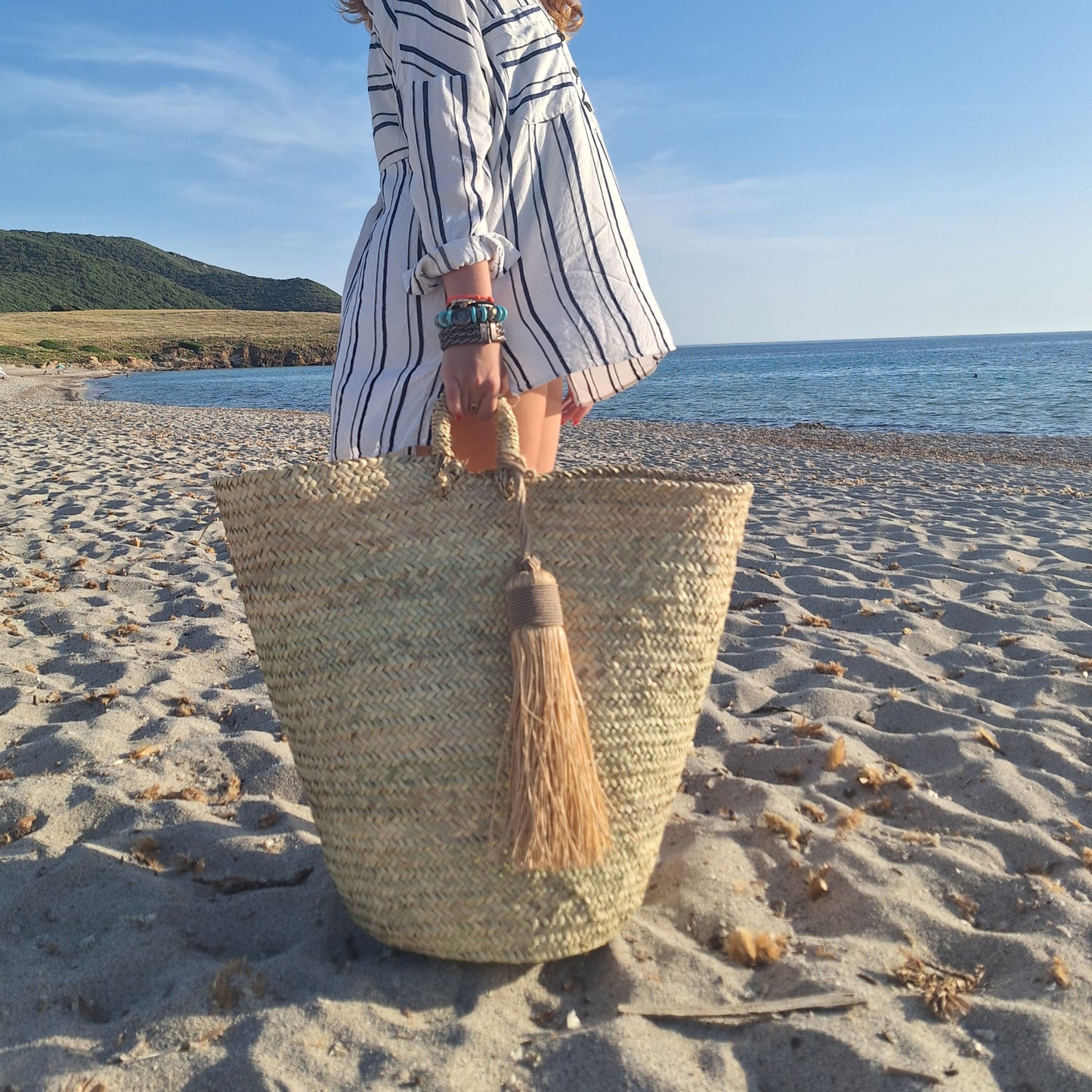 Un grand panier en osier naturel, fait main, orné d’un pompon en raphia. Idéal en déco, panière à linge ou panier de plage. Élégant, pratique, et 100 % artisanal.
